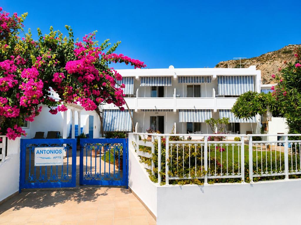 Eingang der Antonios Apartments mit blauem Tor und pink blühender Bougainvillea